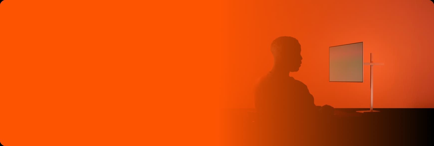 Orange background with man sitting at computer