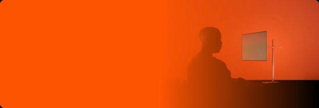Orange background with man sitting at computer